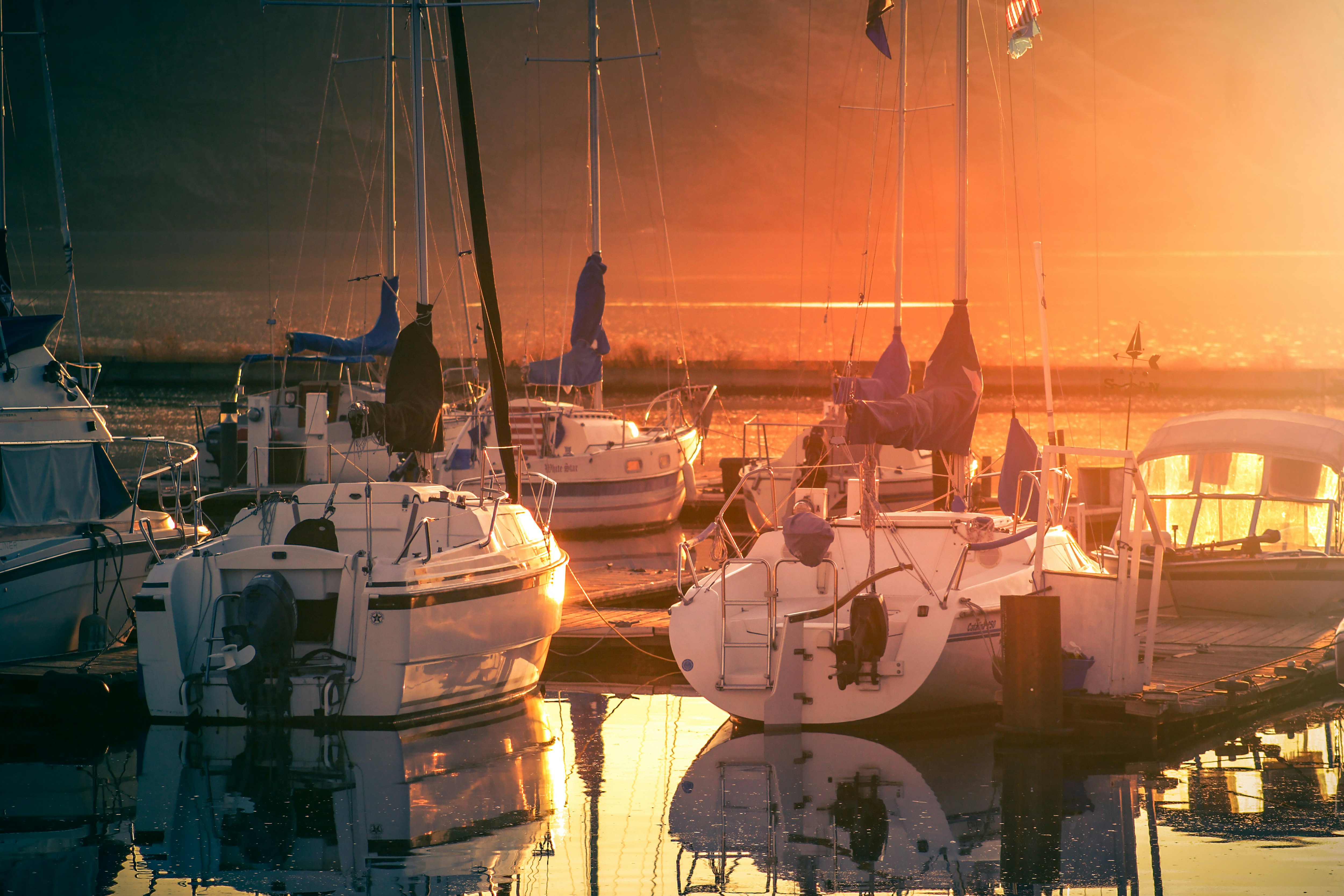 white and brown sail boat on body of water during sunset